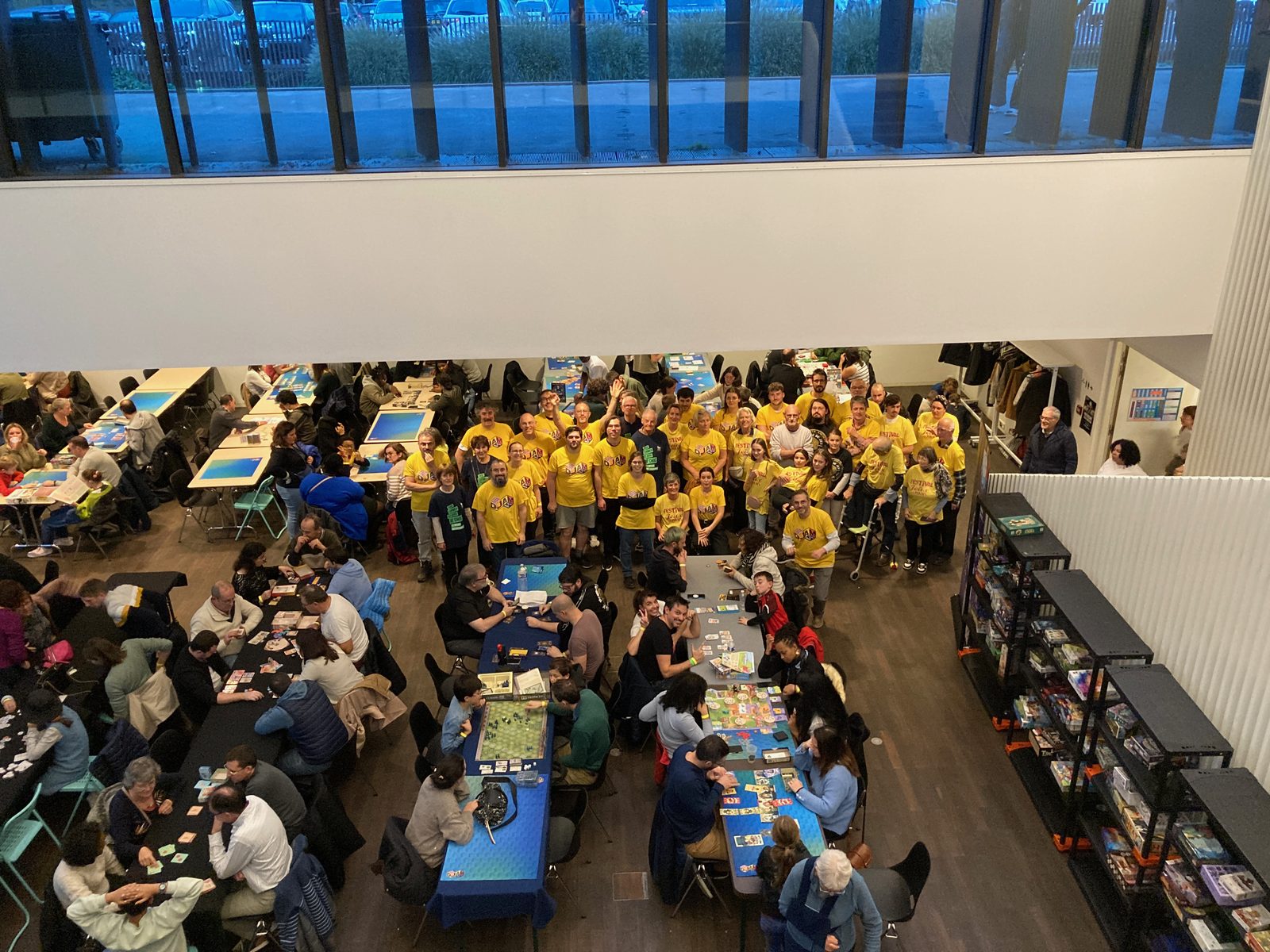 Les bénévoles du festival, en t-shirt jaune, au milieu des tables du Forum pendant l'édition 2025 (photo : DJAM – Les Heures Ludiques)